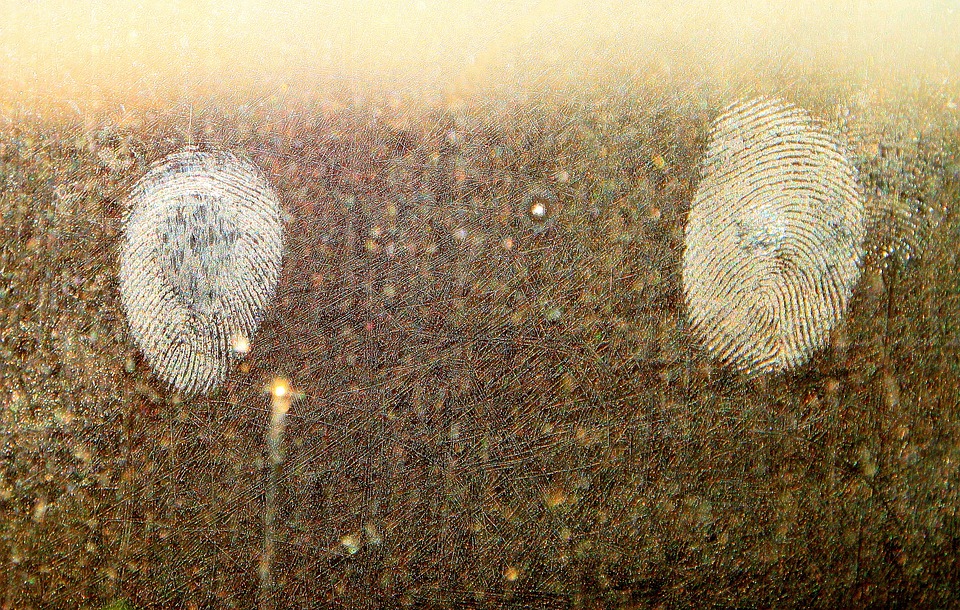 imagem de duas digitais impressas em um vidro sujo