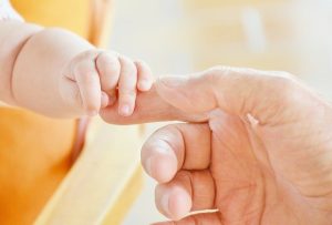 Mão de bebê e de adulto se tocam para evitar maus tratos