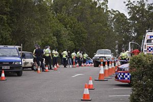 Investigação policial em andamento em uma rua fechada com carros de polícia e cones